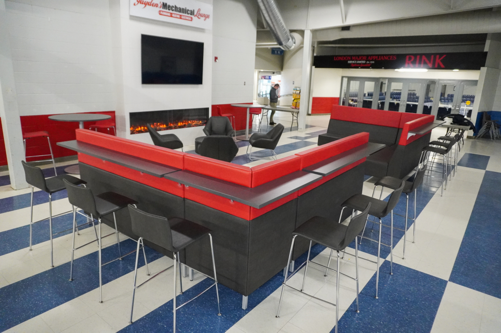 Red and black arena lounge seating with bar-height counters and stools around a modern fireplace