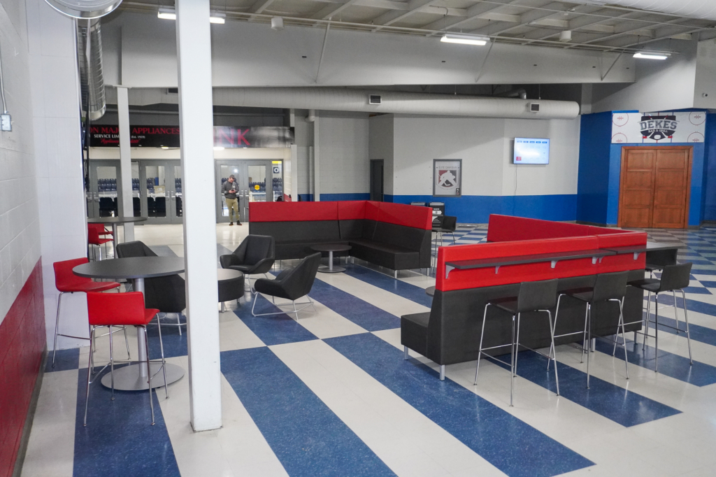 Custom arena lounge seating with integrated counters and stools designed for social gathering in a sports concourse